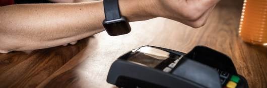 Close-up of man using smart watch to pay in a restaurant. 